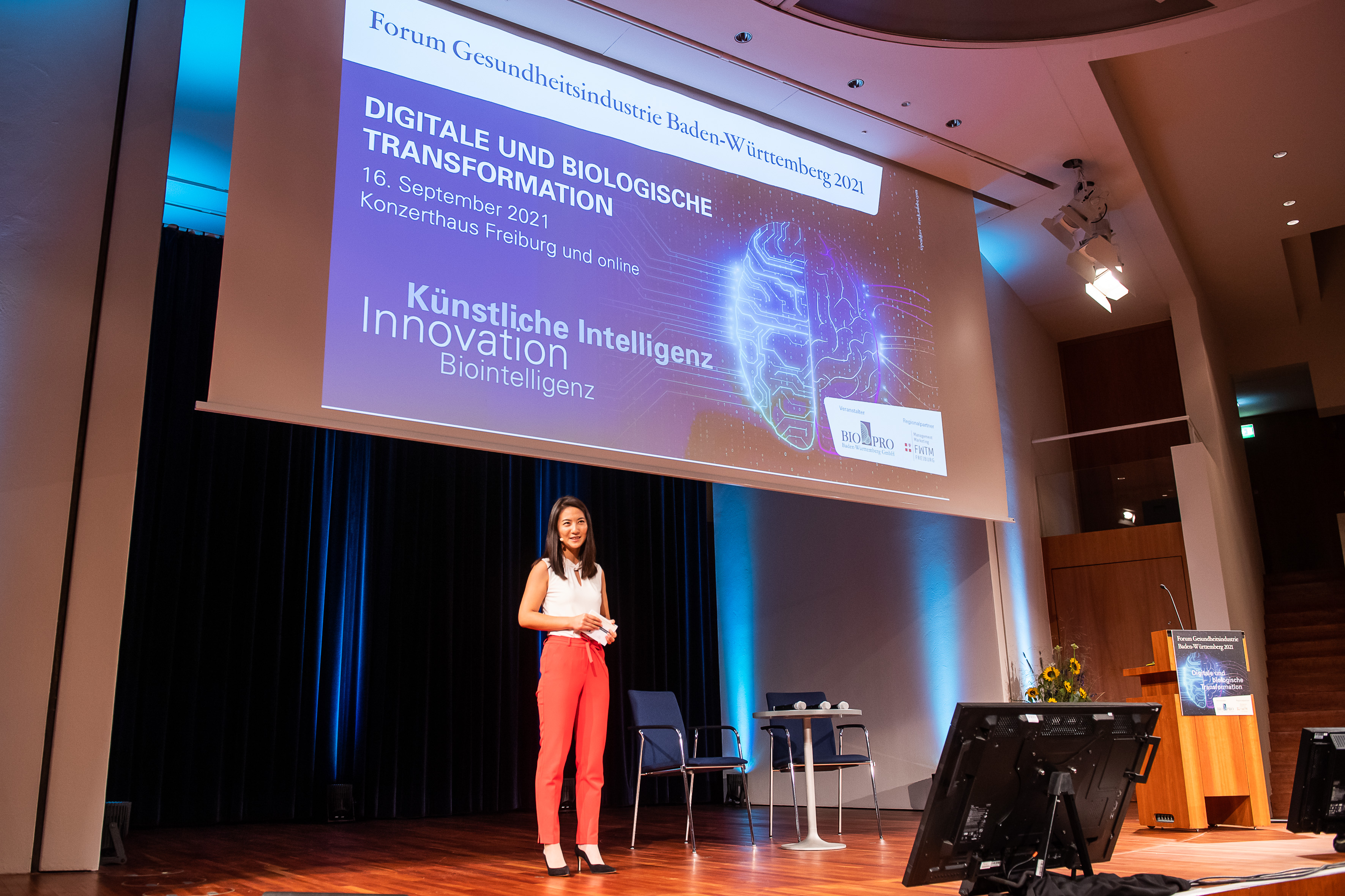 Veranstaltung digitale und biologische Transformation. Eine Frau steht vorne auf der Bühne und hält eine Regel