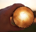 A close-up of a cylindrical object with a finely textured, grid-like surface, illuminated from behind.