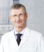 Smiling man with glasses wearing a white lab coat.
